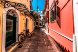 Fototapeta Mosty linowy / wiszący - Colourful Lefkada street with yellow and pink buildings