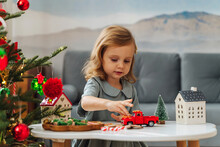 Christmas Holidays. A Little Girl Plays With Toy Cars, Little Houses And Christmas Decorations. Holiday Activity For Kids. Merry Christmas And Happy Holidays!