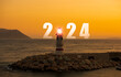 Welcome new year 2024. Lighthouse and the year 2024 on the horizon. It's sunset time. Lighthouse concept for the concept of finding the right direction in the new year, reaching the right goal