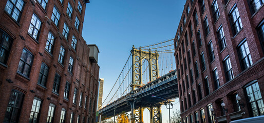 Wall Mural - Manhattan bridge seen from a narrow alley enclosed by two brick buildings on a sunny day in summer