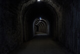 Fototapeta Perspektywa 3d - stone tunnel dark wet old curved stone illuminated with dirt floor in horizontal