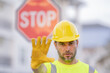 © Volodymyr - Builder showing STOP. Serious builder with stop road sign. Builder with stop gesture, no hand, dangerous on building concept. Man in helmet showing stop road sign.