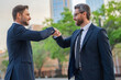 © Volodymyr - Business man shaking hands, giving fist bump. Two businessmen giving fist bump outdoor, friendly team, have positive expressions, demonstrate agreement.