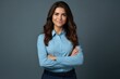 © Adriana - Happy young smiling confident professional business woman wearing blue shirt, pretty stylish female executive looking at camera, standing arms crossed isolated at gray background,
