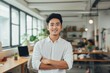 © NikoG - Smiling portrait of a happy young asian man working for a modern startup company in a business office