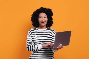 Poster - Happy young woman with laptop on orange background