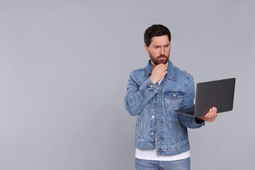 Canvas Print - Confused man with laptop on light grey background. Space for text