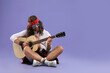 © New Africa - Stylish hippie man with guitar on violet background, space for text
