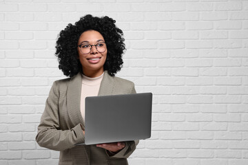 Poster - Young businesswoman using laptop near white brick wall. Space for text