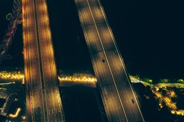 Wall Mural - Top-down view of fast-moving cars on a highway, intense traffic during rush hour at a city crossroad, modern multi-level intersection with beautifully moving vehicles.