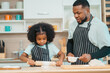 © chokniti - Kind African american parents teaching their adorable daughter how to cook healthy food, free space of kitchen, Happy black people family preparing healthy food in kitchen together