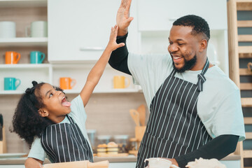 Wall Mural - Kind African american parents teaching their adorable daughter how to cook healthy food, free space of kitchen, Happy black people family preparing healthy food in kitchen together