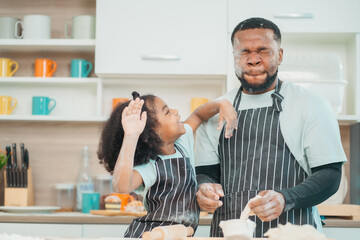 Wall Mural - Kind African american parents teaching their adorable daughter how to cook healthy food, free space of kitchen, Happy black people family preparing healthy food in kitchen together