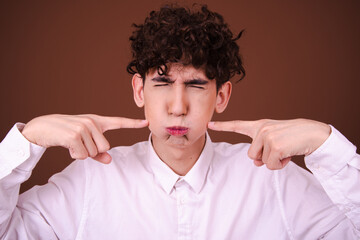 Wall Mural - Funny young man posing on a brown background. Different emotions.