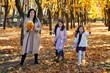 © soleg - mother and daughters are in autumn city park, happy people walking together, family with children, playing with yellow leaves, beautiful nature, bright sunny day