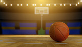 Fototapeta Sport - Basketball ball on wooden floor and sport arena with tribunes and lights in blurred background
