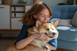 © Westend61 - Smiling woman embracing Welsh Corgi dog in living room