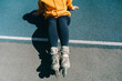 © Westend61 - Woman wearing roller skates sitting at sports court