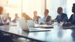 © Vahid - Panoramic view of business meeting in boardroom. Focus on office table and blurred people on backdrop.