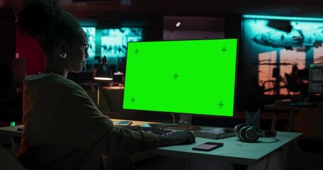 Fototapete - Portrait of Creative Black Woman Sitting at Her Desk Using Desktop Computer with Mock-up Green Screen. Female Specialist Working at Night in Game Development Startup, Finishing Details on a Project