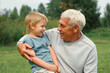 © Marina Demidiuk - Grandfather and grandchild baby have fun during walk In Park. Happy family time. Old man grandpa hugging 4 years child boy at summer day. Smiling Senior male spending time with his grandson together.
