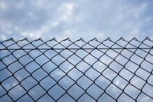 Close-up Of An Old Barbed Wire Fence With A Cloudy Sky In The Background