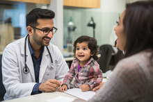 Male Pediatricians Playful With Little Child While Check Up