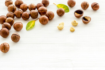 Wall Mural - Shelled macadamia nuts with green leaves. Healthy snack background