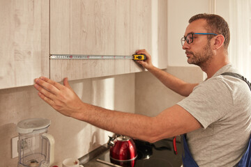 Wall Mural - Handyman fixing kitchen cabinets in the apartment.