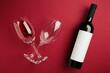 Flat lay of lying red wine bottle with glasses for tasting on dark red background