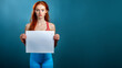 © MQ-Illustrations - Sporty woman with red hair, wearing red tank top and fitness clothing, holding sign, blue background