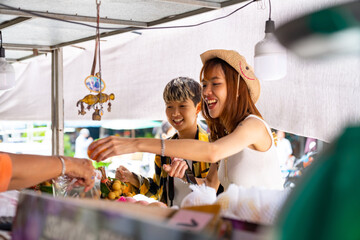 Wall Mural - Group of Happy Asian people tourist buying and eating street food with using mobile app on smartphone scan QR code making online payment during travel local town in Thailand on summer holiday vacation