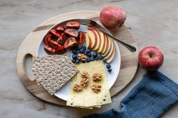 Wall Mural - Simple Low carb meal with fiber crispbread, cheese, tomatoes, apples and walnuts on a plate