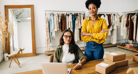 Wall Mural - Female small business owners looking at the camera in their clothing store