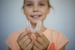 © evgeniia_1010 - transparent mouth guard made of silicone, for straightening teeth in children, in a girl's hand, in daylight. Hygiene, dental care, occlusion correction, new technologies