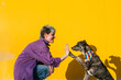 © VISTA by Westend61 - Smiling lesbian woman giving high-five to dog in front of yellow wall
