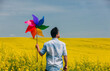 © VISTA by Westend61 - Man holding colorful pinwheel toy in rapeseed field