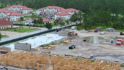 Wall Mural - Aerial view of unfinished wooden frame of apartment building ready for mounting roof beams under construction. Development of residential housing in american suburbs. Real estate market in the USA