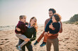 © Marko Geber - Young happy family walking on a sandy beach during winter