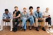 © dikushin - Front view of multicultural and different ages professional business people for vacancy in casual clothes sitting on chairs in row using mobile phones, while waiting job interview on white background