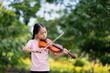 Cute Asian little girl playing the violin in the park