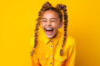 a little girl with pigtails laughing on yellow background. happy childhood concept. enjoy