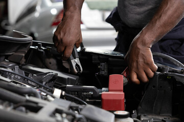 close up mechanic worker hands holding battery cable for jumping battery of a car in automobile repair shop