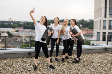 Wall Mural - Yoga practitioners taking selfie on phone on roof terrace