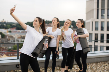 Wall Mural - Yoginis taking self-photo on mobile after outdoor exercises