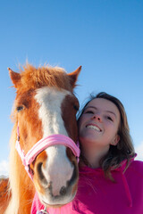 Wall Mural - Selfie time, pretty young girl and her chestnut pony horse having a photo taken together in selfie style, smiling happy and with a blue sky backdrop.