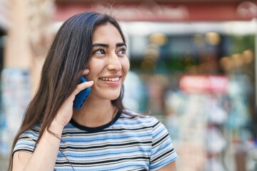 Wall Mural - Young hispanic girl smiling confident talking on the smartphone at street