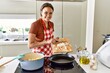 © Krakenimages.com - Young beautiful hispanic woman smiling confident pouring onion on cooking pan at the kitchen