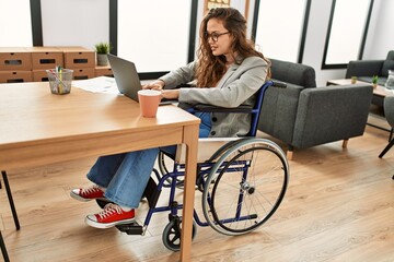 Canvas Print - Young beautiful hispanic woman business worker using laptop sitting on wheelchair at office