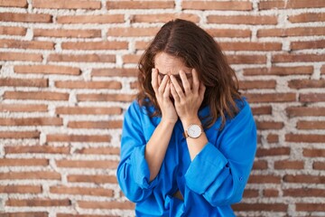 Sticker - Beautiful brunette woman standing over bricks wall with sad expression covering face with hands while crying. depression concept.